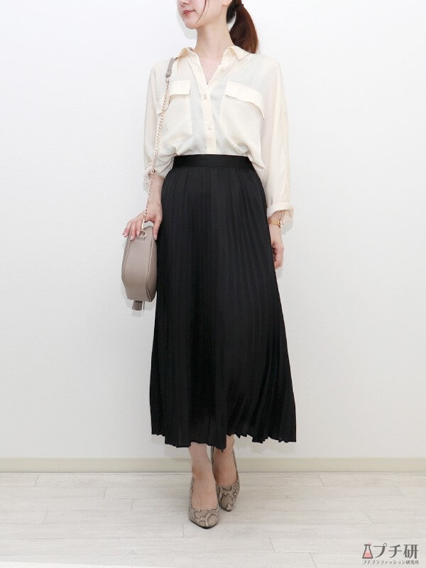 ベージュバッグ×白シャツ×黒プリーツスカートのほんのりトレンドライクなきれい目フェミニンスタイルの画像