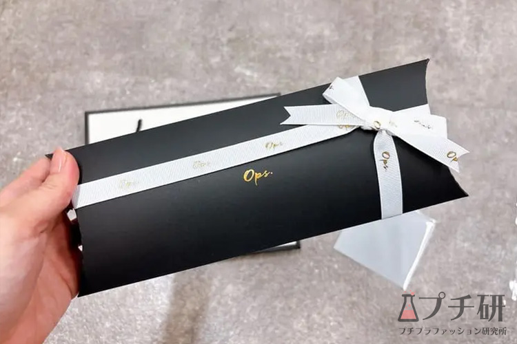 Ops.のロゴ入り白リボンが結ばれた黒いギフトパッケージ